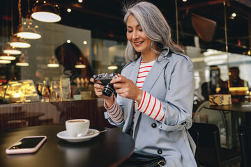Attractive mature woman with camera in cafe