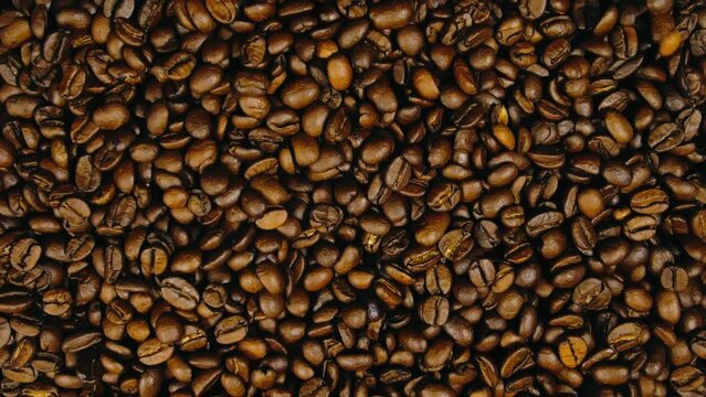 The coffee beans spin rotate quickly fast fly, dispart, splash to the sides with centrifugal coriolis force. The video is in reverse. Twist, create pattern, make design picture. Pressurized air wind.