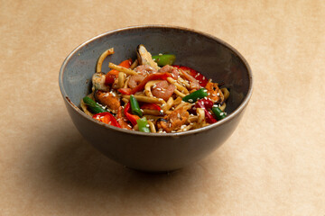 Wok with seafood in a plate on a brown background.