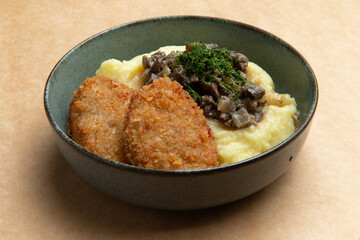 Chicken cutlets and mashed potatoes in a plate on a brown background.