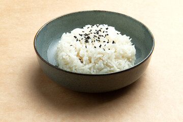 Cooked rice in a plate on a brown background..