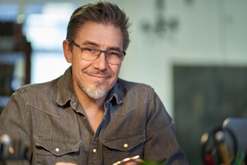 Portrait of middle aged bearded guy at home. maturee handsome man smiling, looking at camera, working at home, using laptop computer, wearing eyeglasses, spectacles.