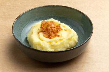 Mashed potatoes in a plate on a brown background.