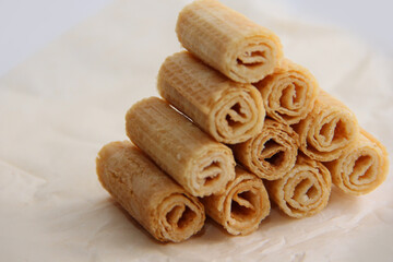 cookies on a plate, a mountain of waffle tubes on parchment paper,