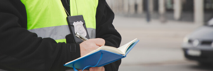 Handsome police officer in a reflective vest writing a ticket