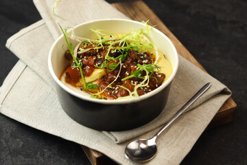 A traditional Hungarian dish is bograch or thick meat red goulash with lentil puree, served in eco paper bowl on a dark background. Restaurant food delivery service and daily ration concept.