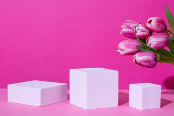 Pink podium for product display on pink with tulips flowers in hard light