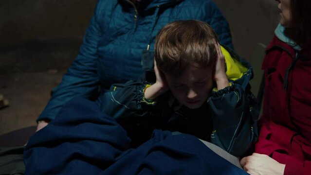 A scared child hiding in the basement with his family