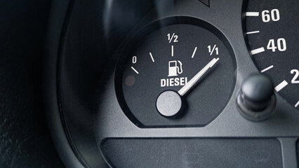 Close-up shot of a diesel fuel gauge in a car. The meter pointer showing that the tank is completely full. Glare of light present on the gauge glass cover. Copy space 