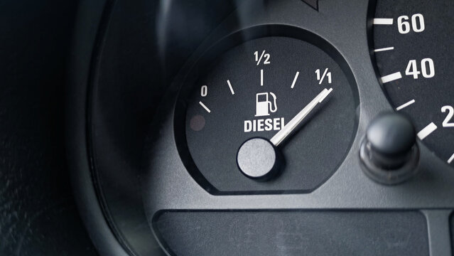 Close-up shot of a diesel fuel gauge in a car. The meter pointer showing that the tank is completely full. Glare of light present on the gauge glass cover. Copy space