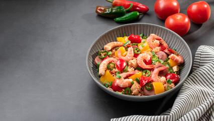 Jambalaya rice with chicken, shrimp, sausage and vegetables in plate on dark table