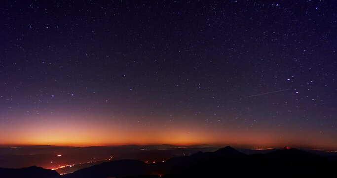 The stars revolve in the starry night sky over the mountains. 4K timelapse video 