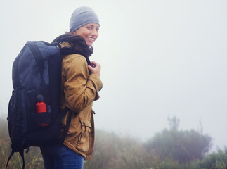 You should join me.... Portrait of a young woman hiking along a trail on an overcast day.