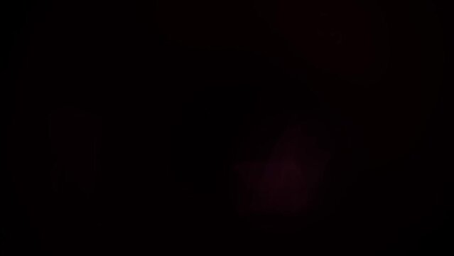 Light is flickering at the black background with anamorph beams. Lens flare of different colours appear and disappear in the darkness. The conception of light effects for filmmakers.