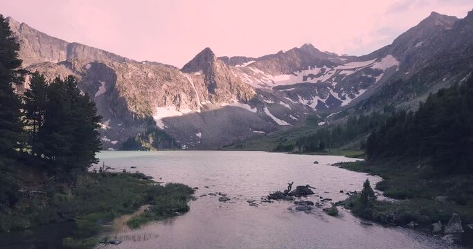 Atmospheric and moody aerial drone video footage of turquoise Krepkoe Lake at sunset in Altai, Russia. National park and natural wonders background
