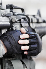 At ease soldier. Closeup cropped shot of the midriff of a soldier holding his gun against his chest.