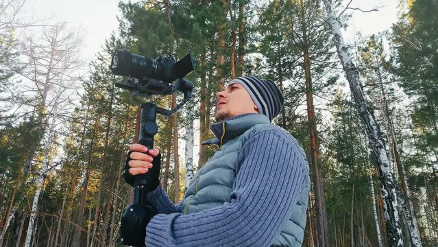 Professional Videographer Holding DSLR Camera on 3-axis Gimbal Stabilization Device in Winter. Pro Equipment Helps to Make High Quality Video Without Shaking. Cinematographer Operator. Slow Motion