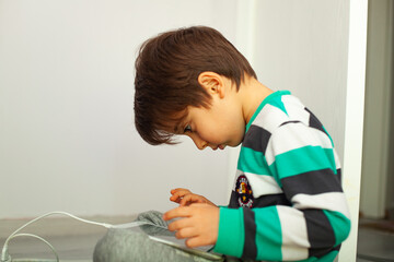 Technology addiction. Child playing with the tablet. Technology addiction is very common among children. 8 years old boy playing with the tablet.