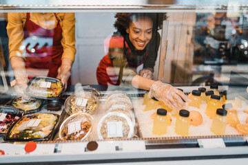 Beautiful African American and Caucasian female workers working in confectionery shop.