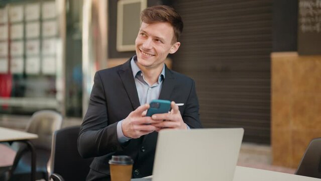 Young caucasian man smiling confident using laptop and smartphone at coffee shop terrace