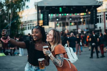 Two beautiful friends taking selfie with a smartphone on a music festival