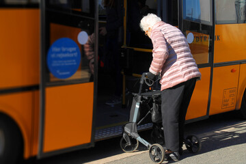 Old lady with a walker entering a city bus in Denmark