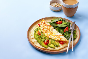 Dish with stuffed Omelette with green vegetables avocado and cherry tomatoes. Breakfast and coffee