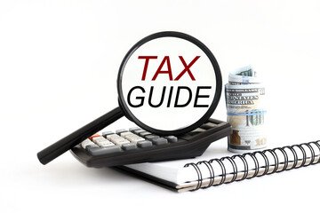 magnifying glass on a notepad, with an information word on a white background. TAX GUIDE
