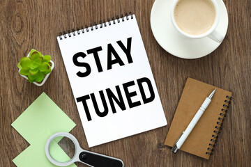 Stay tuned. notepad on a wooden background with text
