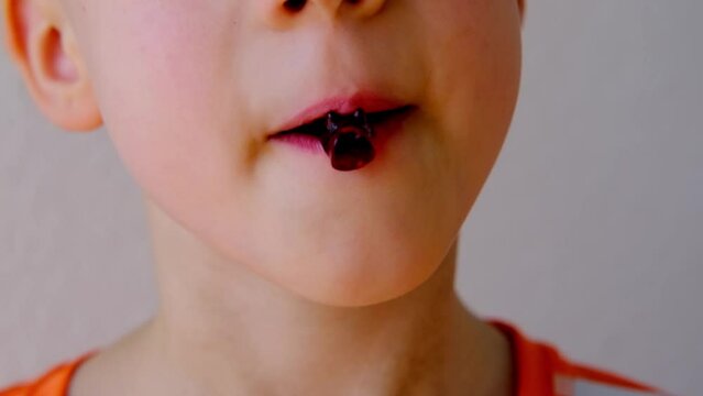 close-up of part of child's face, child, boy 8-10 years old enjoys sweets, wants to eat gelatinous candy, gummy bear, concept of children's delicacy, healthy and unhealthy food, halal food