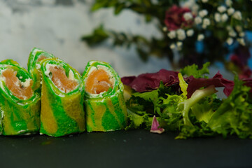 Green pancakes, folded dough rolls, serving pancakes for Shrovetide. Filled with salmon and tender cheese. Zebra dough. Unusual serving food. Cooking, delicious food, colorful food.