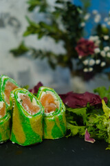 Green pancakes, folded dough rolls, serving pancakes for Shrovetide. Filled with salmon and tender cheese. Zebra dough. Unusual serving food. Cooking, delicious food, colorful food.