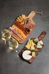 Two white wine glasses with buffet platter with cheese and meats, antipasti, prosciutto, charcuterie.