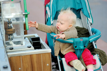 Cute baby girl in a stroller playing water dam simulation at Madurodam miniature park, The Hague, Netherlands