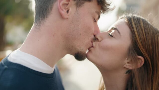 Young couple standing together kissing at street