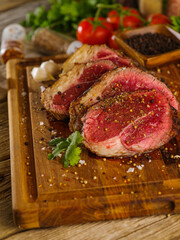 Pieces of juicy steaks from raw pork beef sprinkled with salt and spices on a wooden cutting board. Close-up. The concept is the preparation of meat dishes, home and restaurant cuisine.