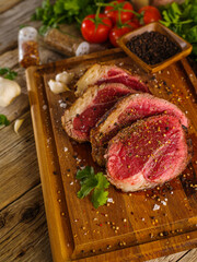 Raw steaks from pork, beef, breaded in spices, on a wooden cutting board. Garlic, greens. Close-up. There are no people in the photo. Food background.