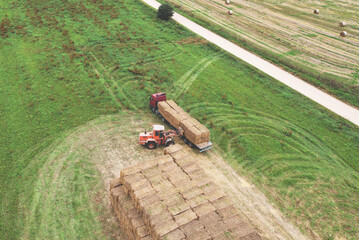 Hay Trailer with round bales. Front end loader unloading round bales. Store hay at farm. Hay rolls...