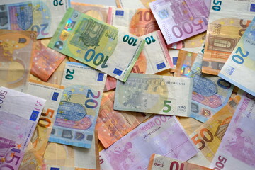 closeup paper 5,100, 50 euro banknotes of european union against background of scattered paper banknotes on table, concept of payments, savings, banking, save up for vacation, cash out currency