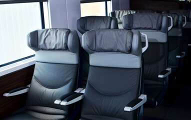 Naklejka premium Seats in the cabin of business class carriage of a passenger high speed train. Modern interior of the urban railway transport. Leather armchair seat on a european double-decker passenger train.