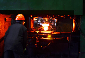 Blacksmith work with red hot iron under a press on metallurgical plant. Metal forging, stamping...
