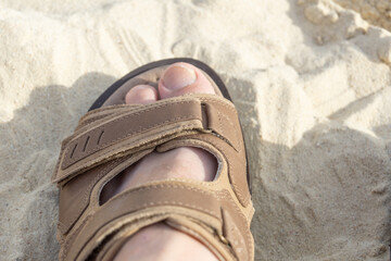 Man's foot in sandals on the sand. The concept of relaxation, sunburn.