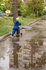 Playful Boy in Colorful Rain Gear Riding a Scooter Through Puddles: Embracing the Joy of Rainy Days