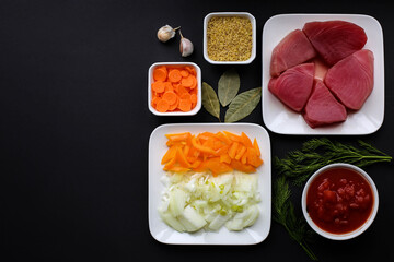 Background for cooking. Ingredients for fish soup. A set of tuna, bulgur, carrots, paprika, onions, garlic, dill, mashed tomatoes, bay leaf. Text space, top view.