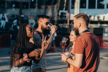 Group of friends drinking beer and having fun at music festival