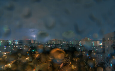 Lightning in a night city through drops on lens