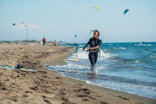 Young sporty woman using control bar to lift her kite up for kitesurfing