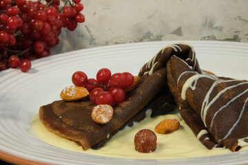 
Pancakes made of white and dark chocolate, decorated with viburnum berries. Sweet pancakes for kids. Shrovetide, Slavic holidays, Traditional flour dishes.