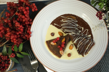Pancakes made of white and dark chocolate, decorated with viburnum berries. Sweet pancakes for kids. Shrovetide, Slavic holidays, Traditional flour dishes.