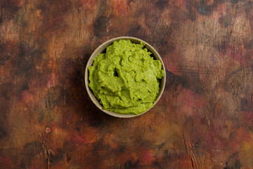 Bowl of freshly prepared fresh guacamole on a wooden background in brown tones. Healthy food rich in omega 3 fats that help prevent cholesterol. Super food.